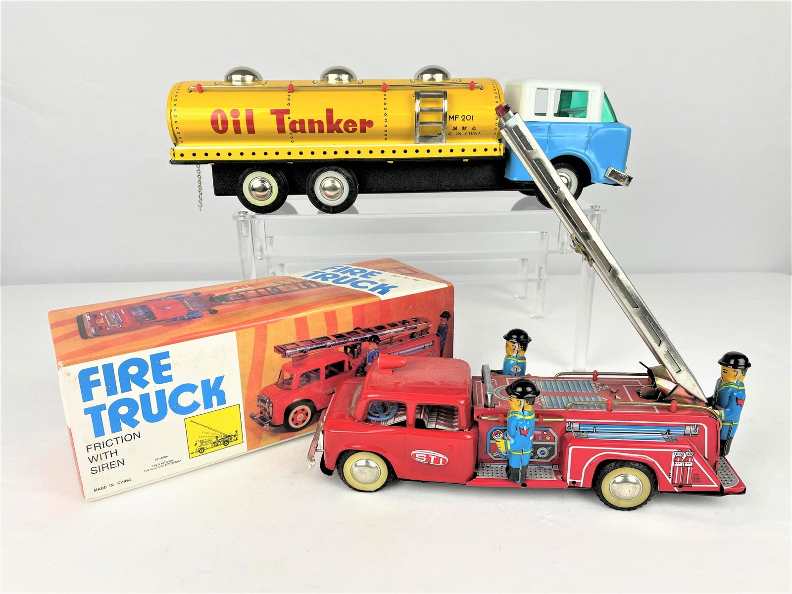 Tin Litho Fire Trucks & Oil Tanker: Group of three (3) later vintage tin litho friction toys including two fire trucks, one in original box (French and English marketing on the box cover), and an oil tanker in its original box. Oil tank