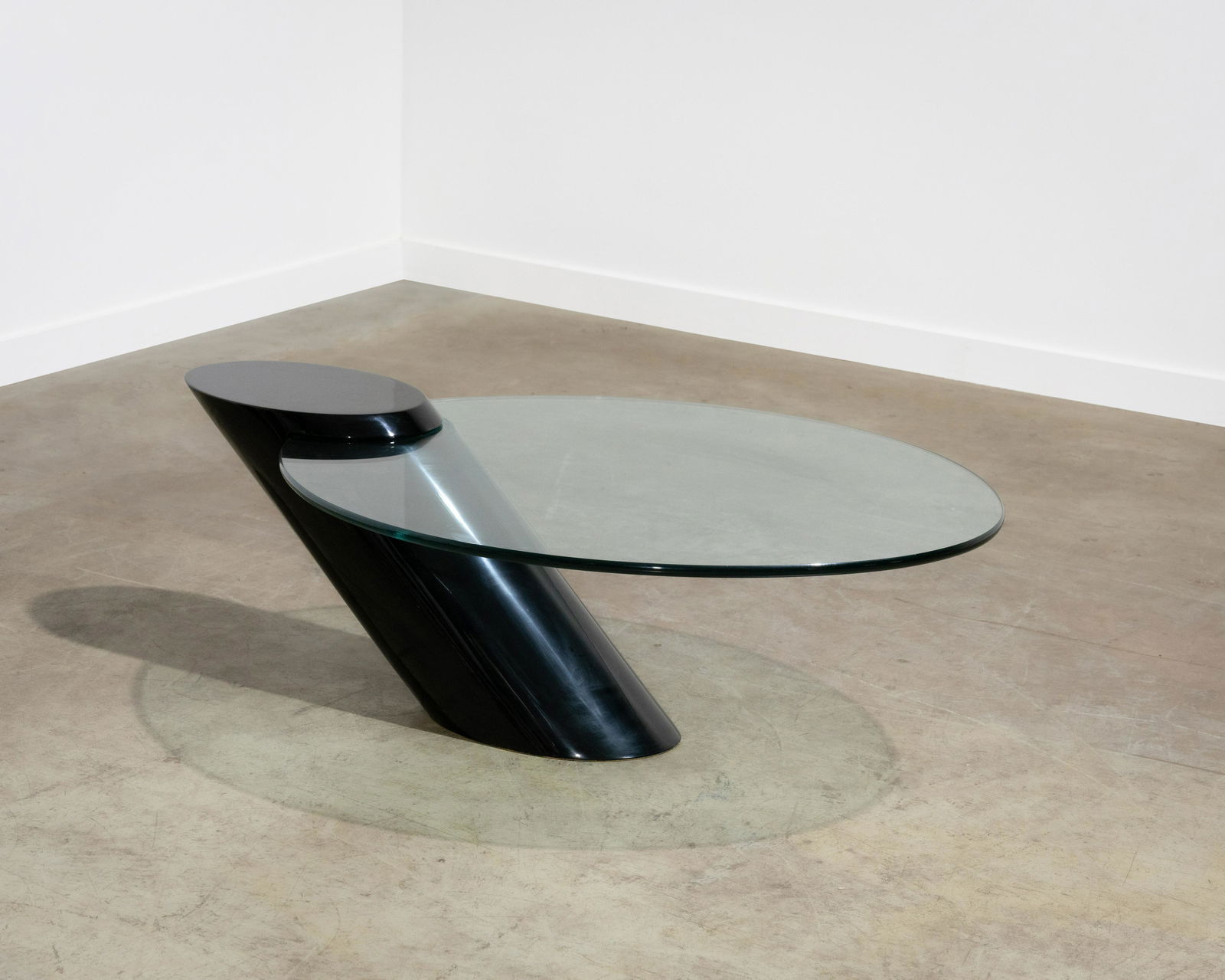 Cantilevered Glass Coffee Table: A cantilevered glass top coffee table with lacquered base, in the manner of Brueton. Dimensions : 17 x 43.5 x 34. All measurements are in inches.