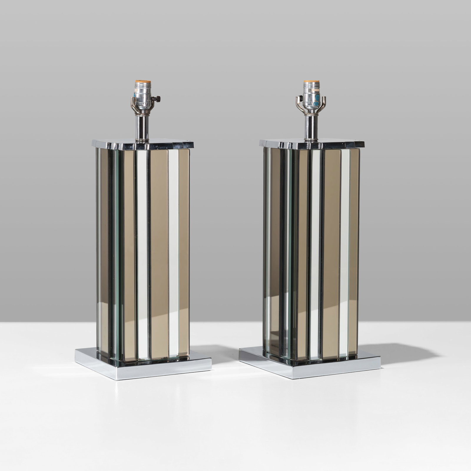 Mirrored Glass Lamps: A pair of smoked and mirrored glass lamps with chrome accents. Unmarked. 22 x 8 x 8. All measurements are in inches. (Height x Width x Depth).