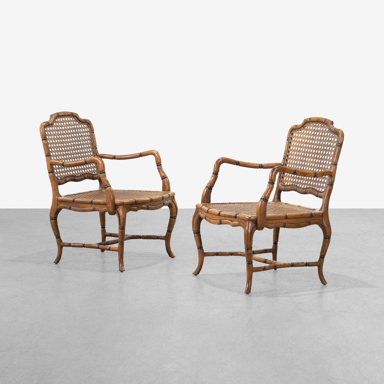 Caned Armchairs: A pair of faux bamboo carved armchairs with canes seats and backs. All measurements are in inches. Height x Width x Depth