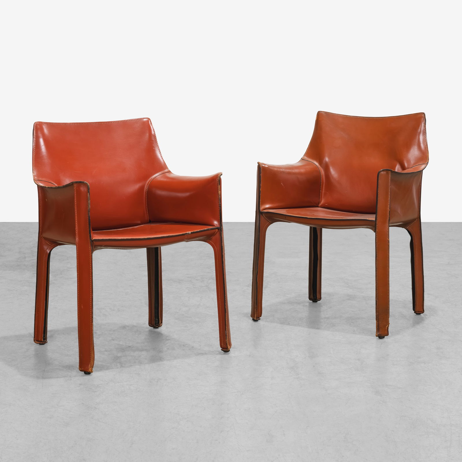 Mario Bellini - Cab Chairs: A near pair of red leather Cab armchairs by Mario Bellini for Cassina, Italy. All measurements are Height x Width x Depth.