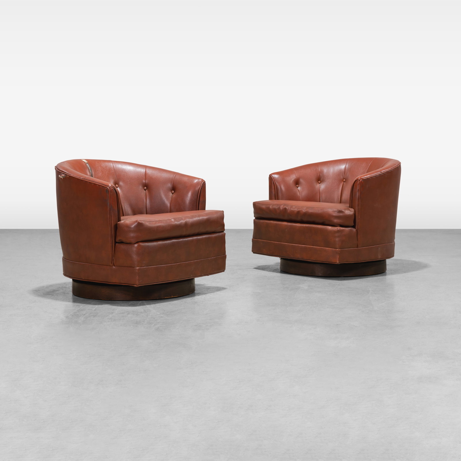 Swiveling Club Chairs: A pair of returning swiveling club chairs on wooden bases in the manner of Milo Baughman. All measurements are in inches. Height x Width x Depth