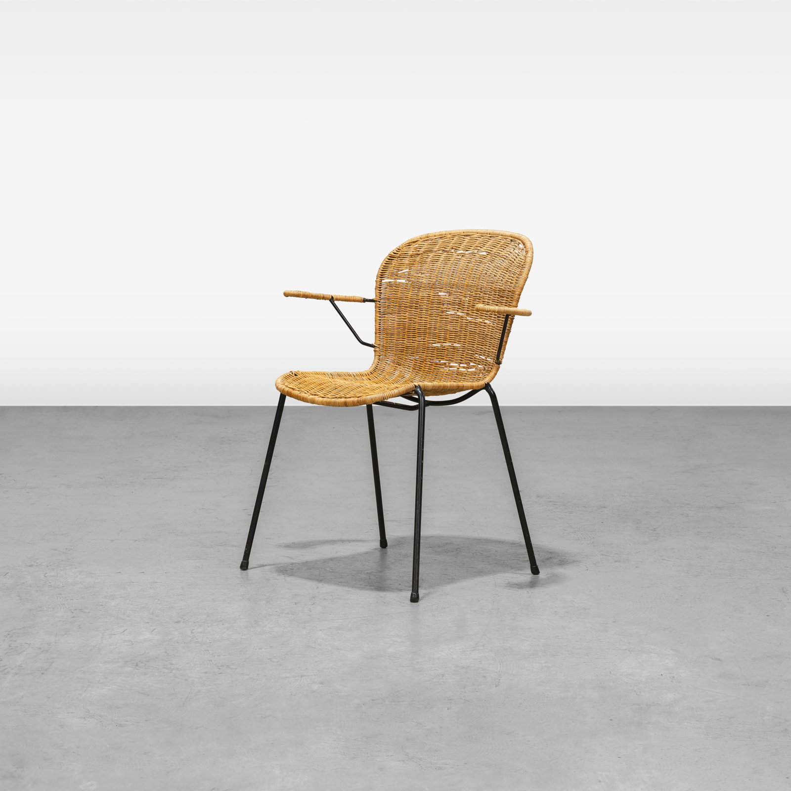 Wicker Armchair: A vintage wicker armchair in the manner of Danny Ho Fong. All measurements are in inches. Height x Width x Depth