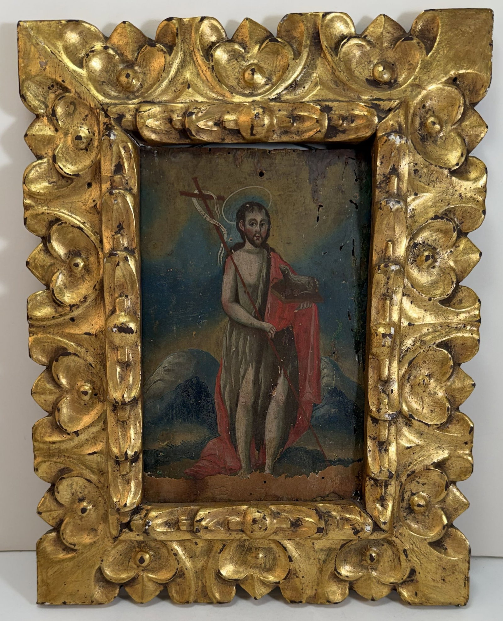 Spanish Colonial Painting of St. John the Baptist, 19th Century: The painting oil on board in a carved gilt wood frame, Saint John the Baptist (San Juan Bautista) shown in the traditional manner, holding the cross and the lamb of God, and depicted wearing a tunic a