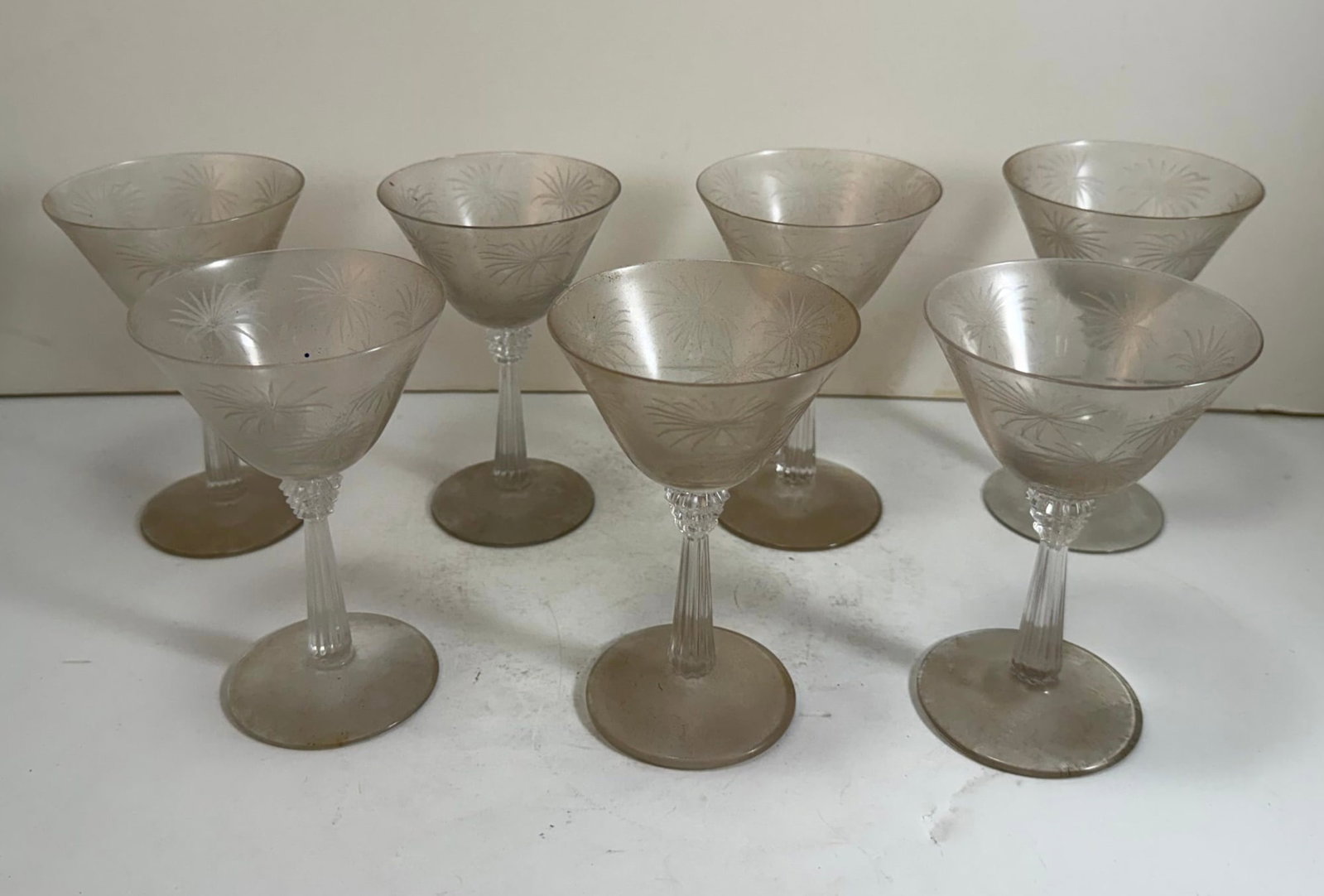 Set of Seven Lido Clear Wine Glasses by Fostoria: With a columnar fluted stem and etched with fireworks or star bursts on the bowl. Height: 5 inches, Diameter: 3 1/2 inches. Weight: each cup approx. 4 oz., approx. 24 oz. for the set.