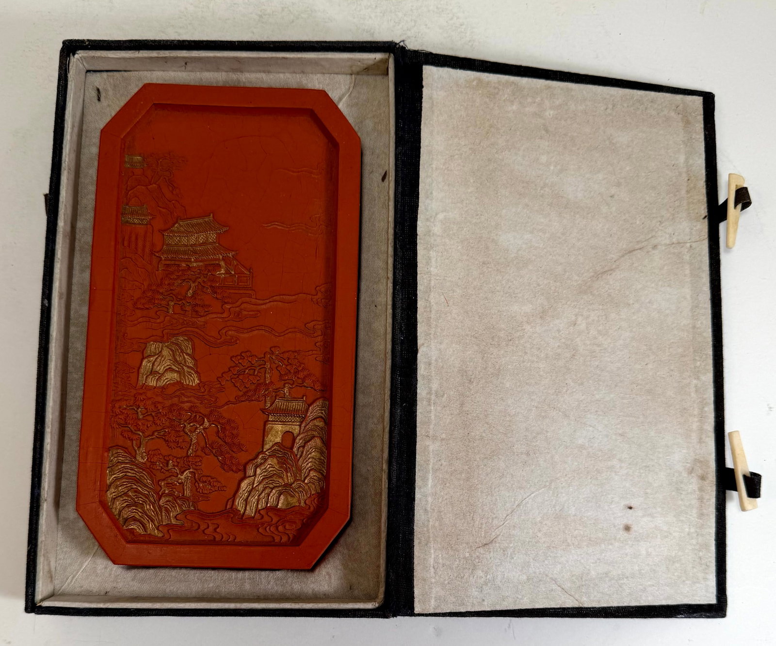 Large Chinese Reddish Brown Ink Cake: With a molded landscape on the front and a molded inscription on the back, some fine cracks on the surface, with a fitted box. The ink cake 7 by 3 3/4 by 3/4 inches, the box 8 1/4 by 5 by 1 1/4