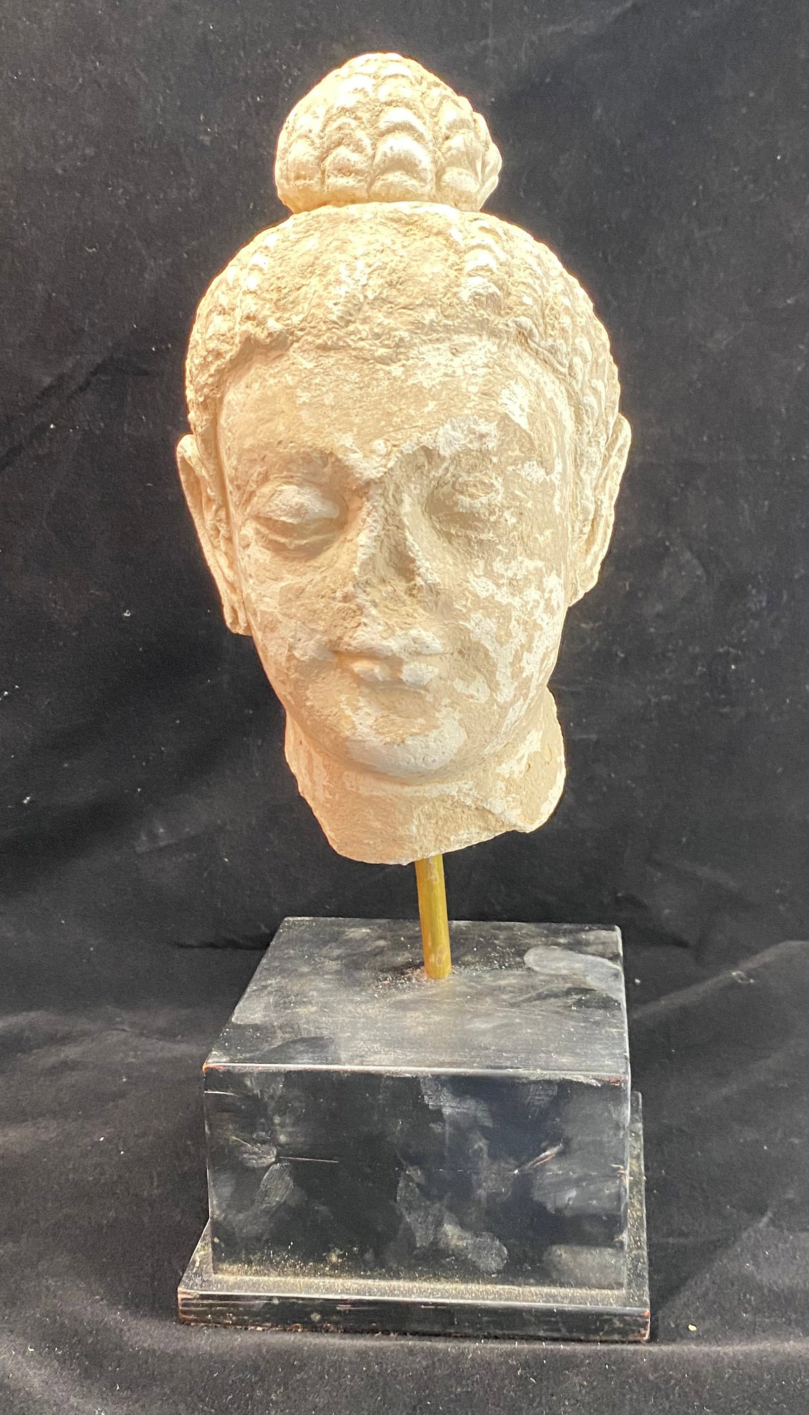 Gandharan Buddha Head, 5th Century AD: Modeled stucco over a stone core, Greco-Buddhist sculpture from Pakistan or Afghanistan, a synthesis of Hellenistic techniques and Asian motifs, this head exemplifies the wavy hair and a serene