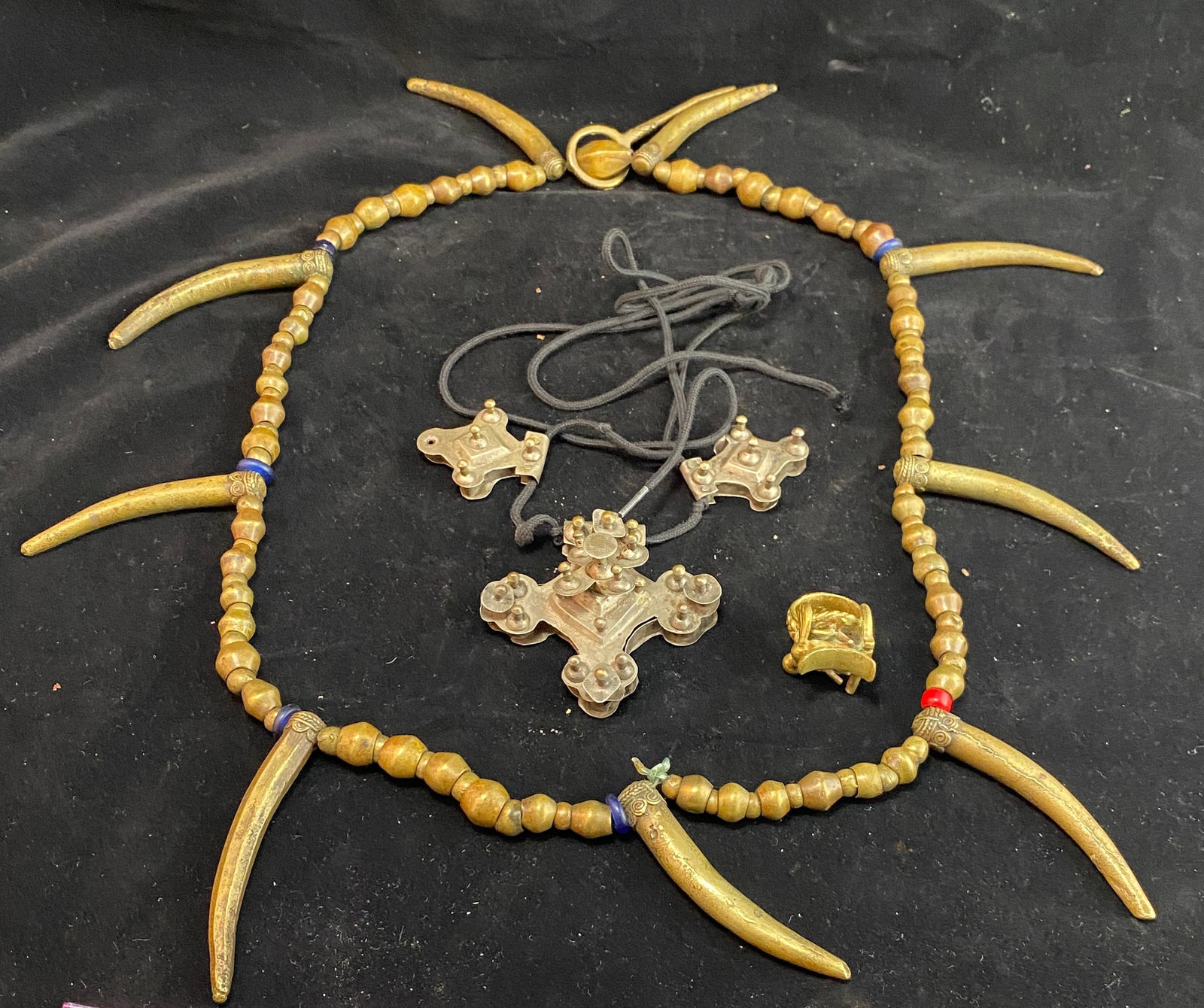 Two African Necklaces and an African Akan Brass Elder Ring: The ring in the form of a Chiefs Stool, and originally worn by the Chief to represent his authority. Length: tusk necklace 36 inches long. Necklace with crosses: larger cross 3 1/4 by 3 by 1 1/4 inche