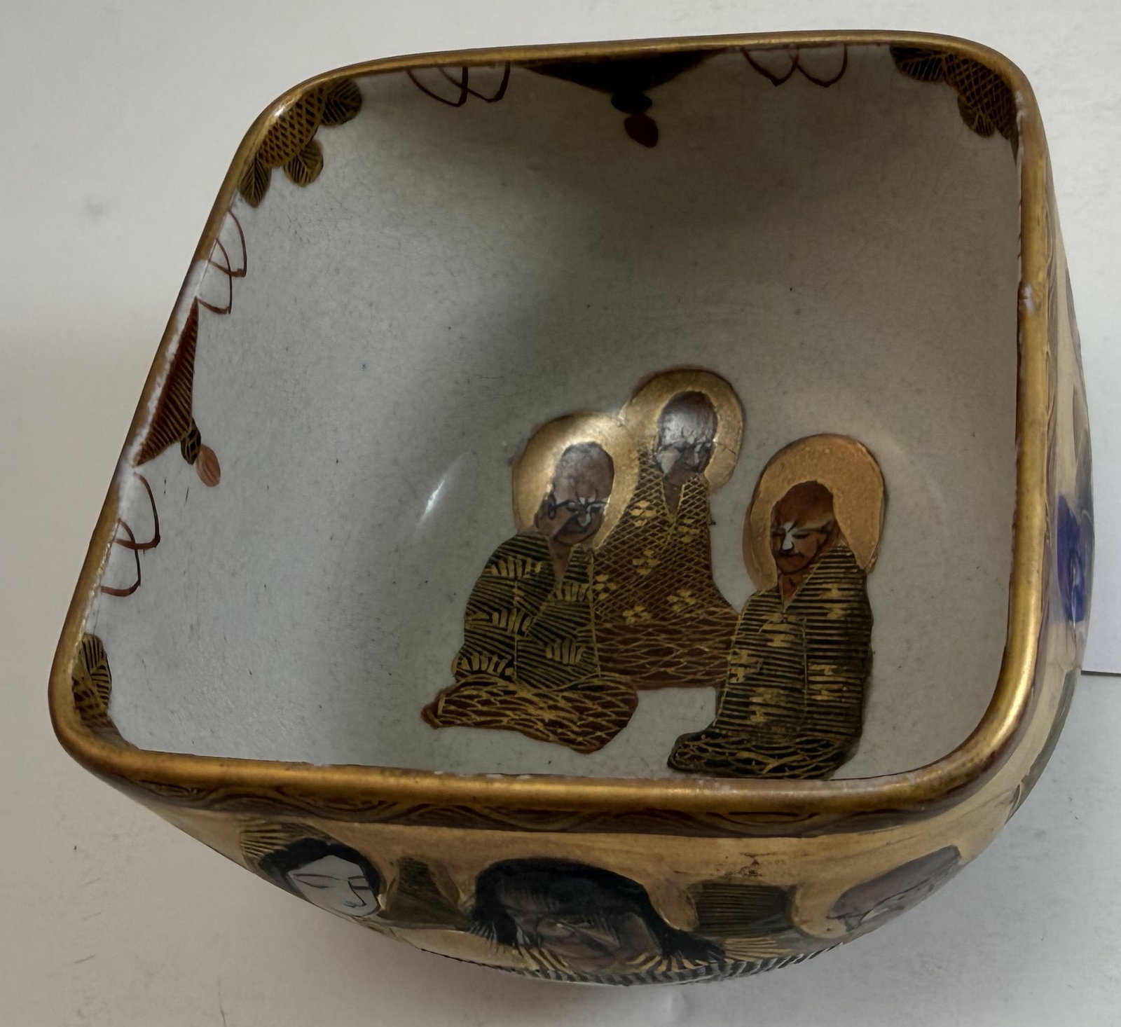 Japanese Satsuma Square Form Bowl, Signed, early 20th Century: with a Shimazu crest on the underside, decorated with immortals, minor rubbing to the gilding. 4 1/2 inches square, Height: 3 inches. Weight: 12 oz.