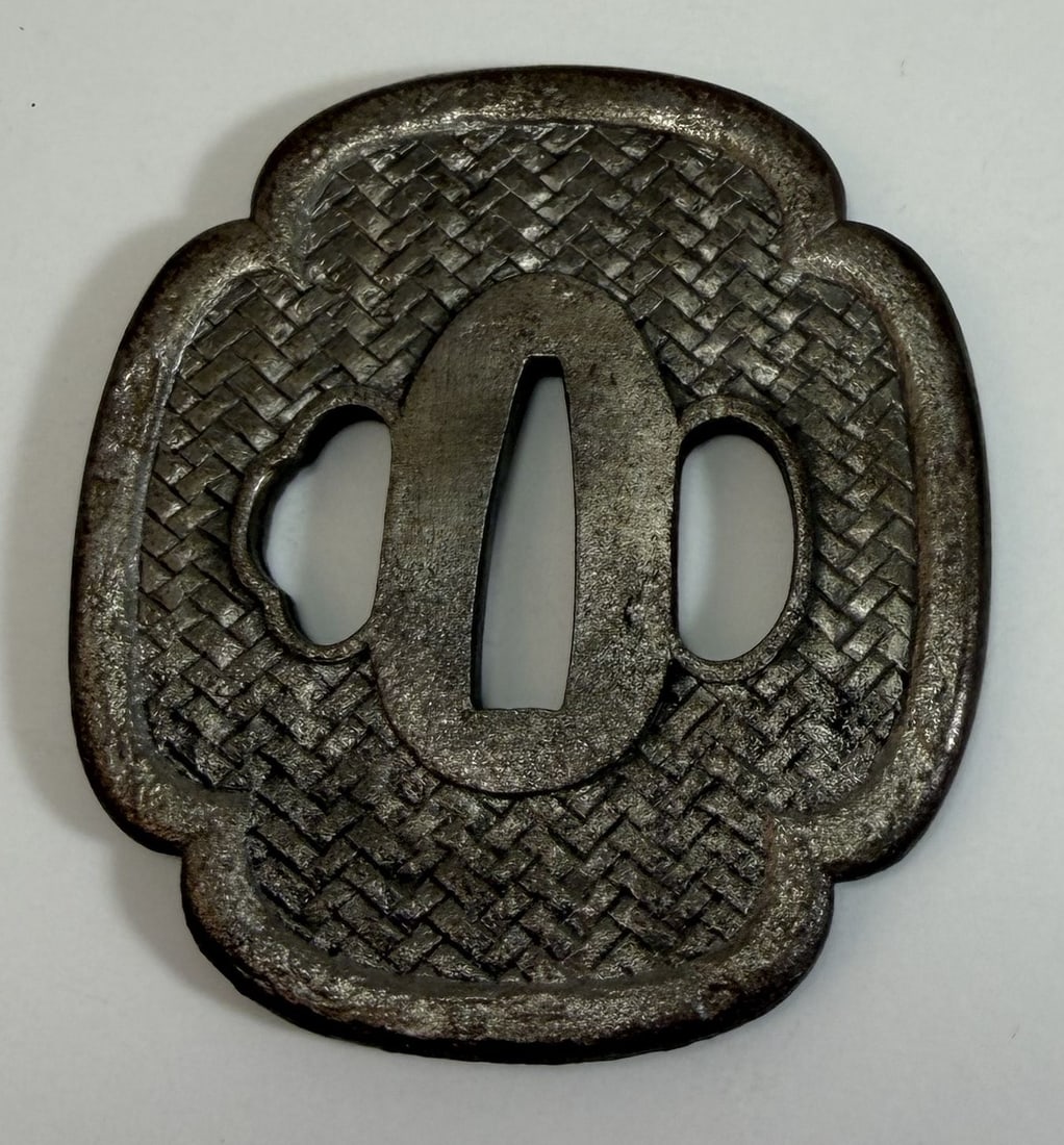 Japanese Iron Tsuba with a Woven Pattern: With wear as expected with age and use. 3 inches by 2 3/4 inches. Weight: 5.3 oz. This item is at our New York location.