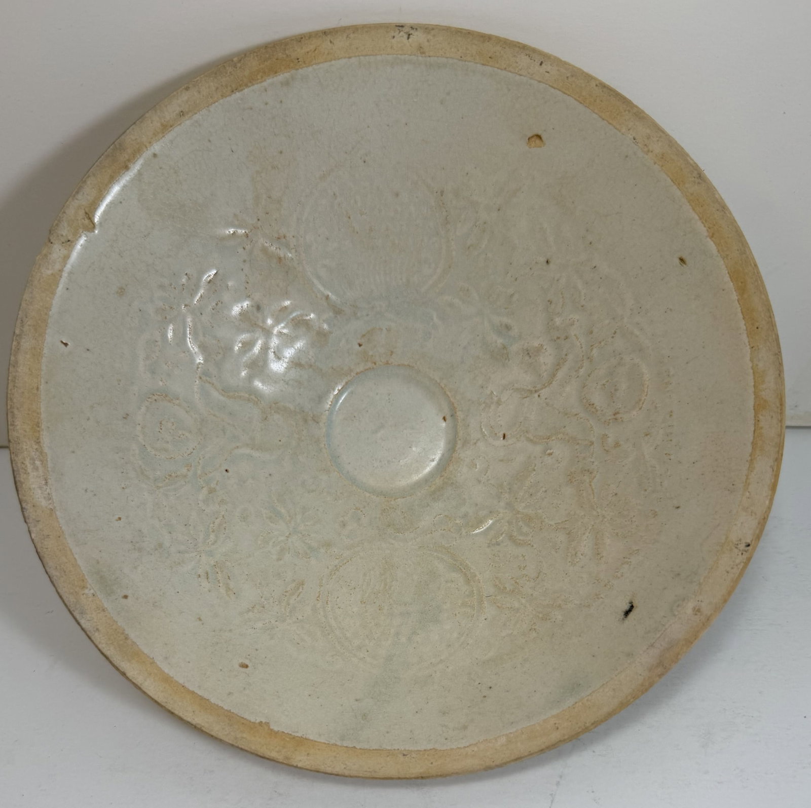 Chinese Qingbai Bowl with Molded Decoration, Likely 12th Century: Some wear and flaking to the glaze, some scattered chips, crazing to the glaze. Diameter: 7 inches, Height: 2 1/8 inches. Weight: 9 oz. This item is at our New York location.