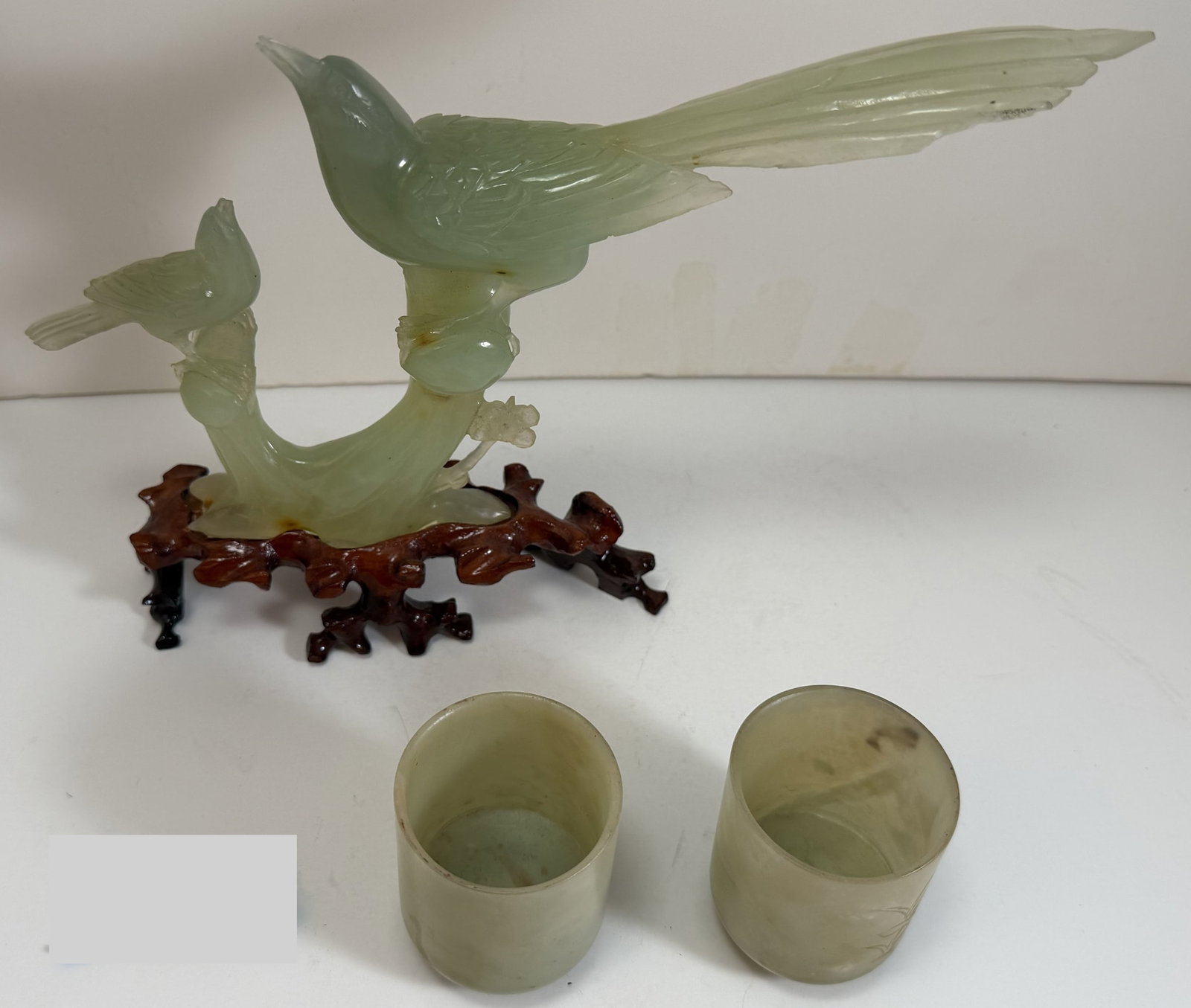Chinese Hardstone Carved Bird Group and a Pair of Hardstone Tea Cups: The cups with carved flower decoration, the bird form group with a fitted wood stand. The bird group with a chip to the tail. The birds: Height: 6 1/2 inches, Width: 10 1/4 inches, Depth: 1 1/2 inches