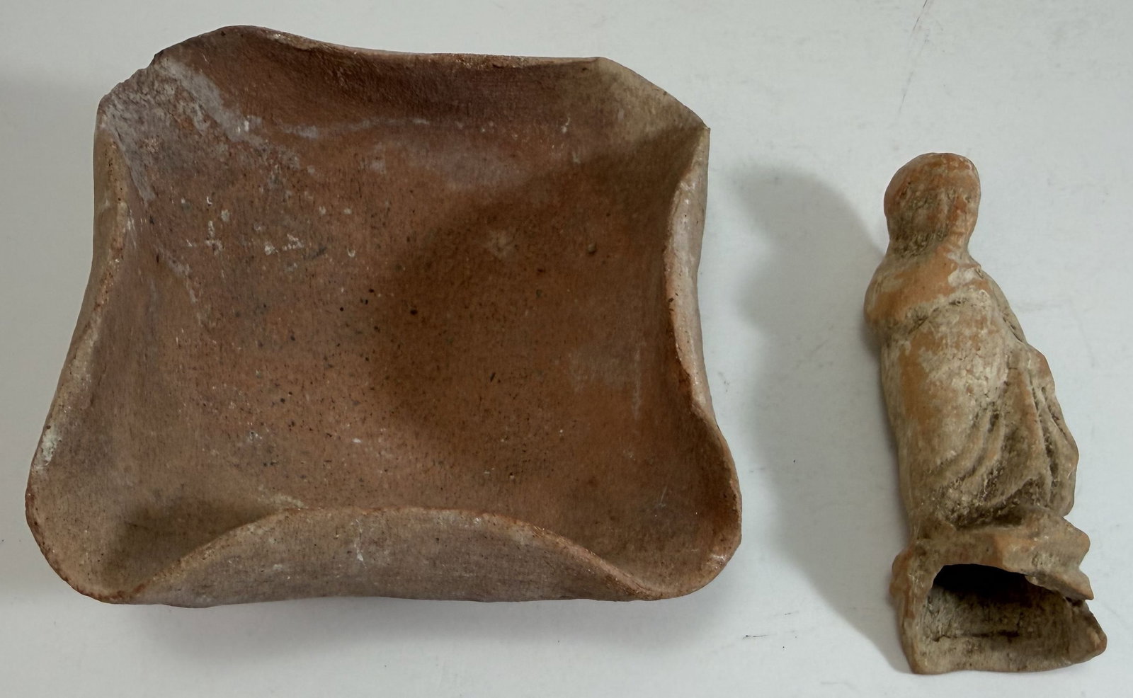Ancient Greek Terracotta Figure and a Terracotta Dish: Wear as expected with age and use, some breaks, including to the base of the figure. The figure: 3 3/4 1 1/8 x 1 inches. The dish: 4 inches square, 2 inches tall. Weight: 8 oz.
