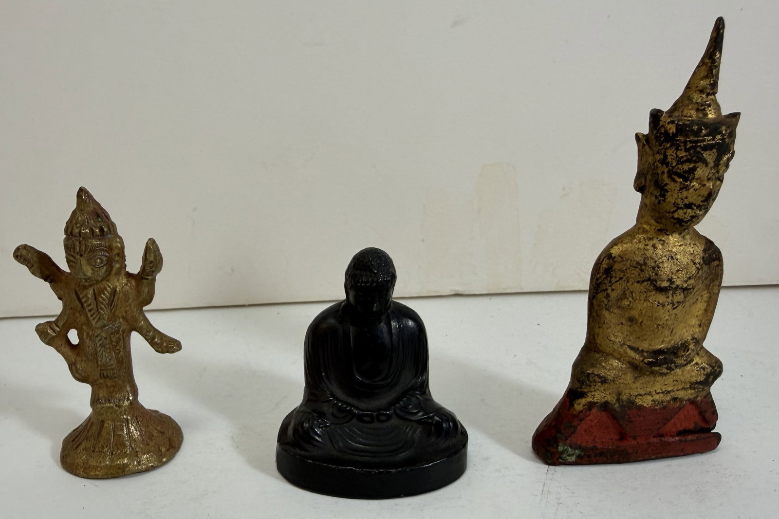 Three Asian Metal Figures of Deities: Each likely for a home shrine; the first a Thai seated figure of Buddha, the second an Indian brass figure with four arms, the third a Japanese metal figure of Buddha with an impressed inscription on