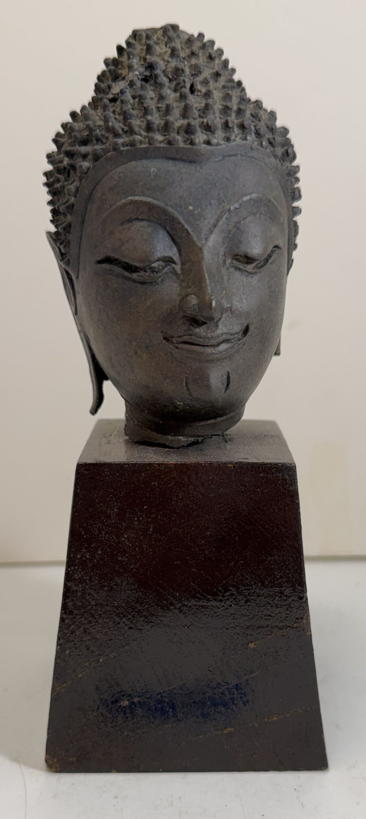 Thai Bronze Head of Buddha: The figure with a serene blissful expression, likely a fragment from a larger piece, lacking the original flame form ushnisha. Height: the head 3 3/4 inches, overall 6 1/2 inches with the stand,