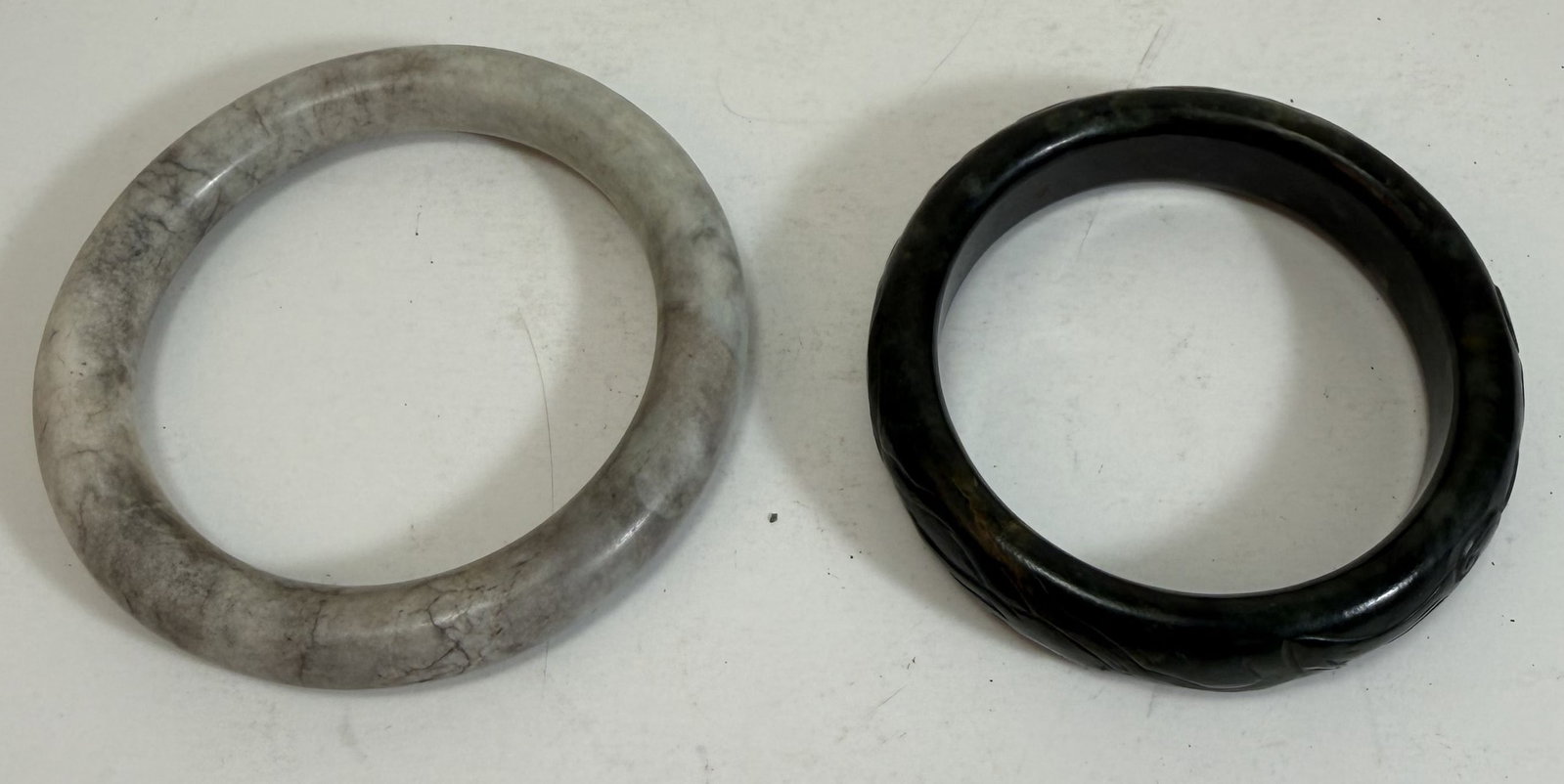 Two Chinese Jade Bracelets: The grey jade bracelet with a fissure in the stone. Diameter: 3 3/8 inches on the outside and 3 inches on the outside. Weight: 5 oz. total