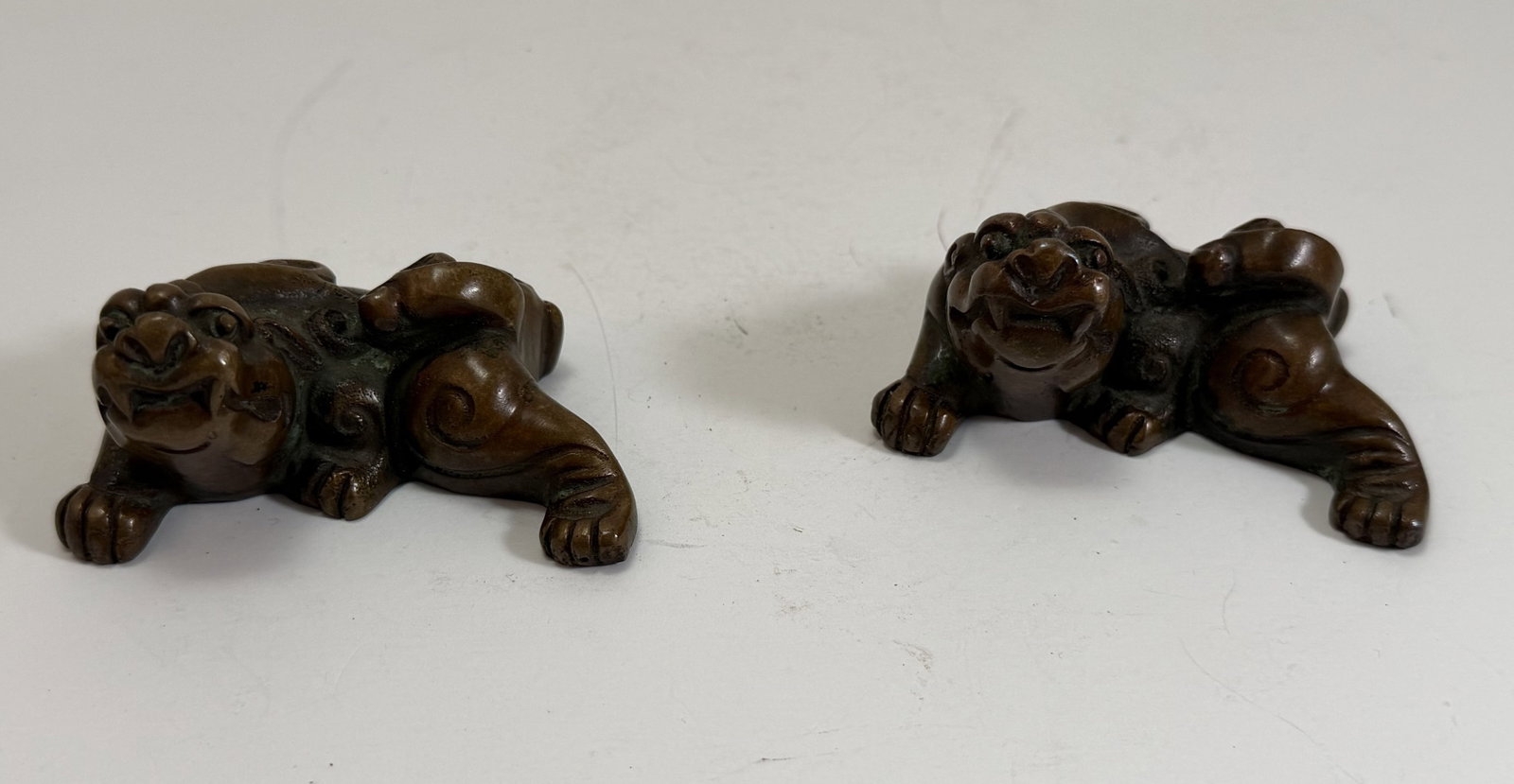 Two Chinese Mythical Beast Form Bronze Scroll Weights: Length: each 3 1/4 inches, Depth: 2 3/8 inches, Height: 1 3/4 inches. Weight: 1 lb. 1 oz. Total. This item is at our New York location.