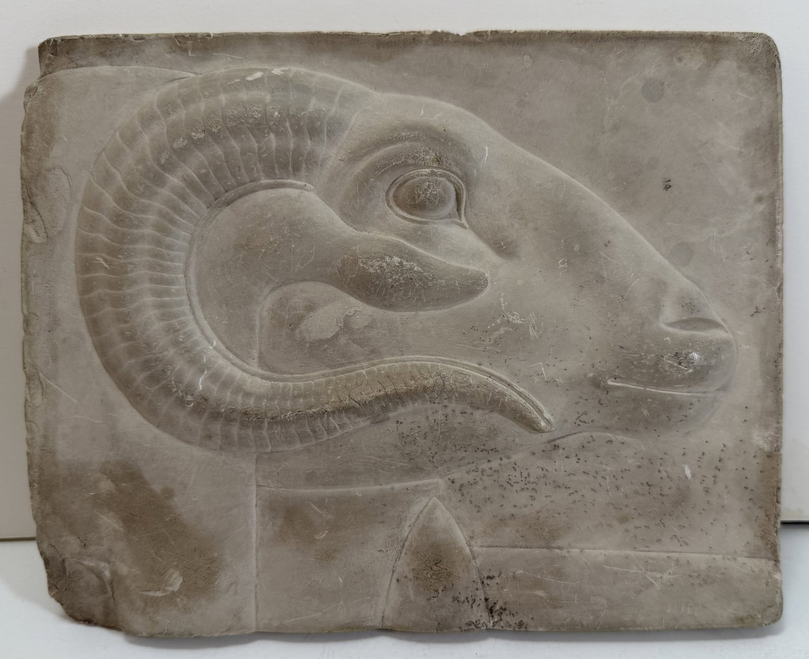 Egyptian Relief Carved Gypsum Panel of a Rams Head, Khnum: Likely a copy after the antique, some staining, chips and scuffs, with some filled areas on the back. 6 3/4 x 8 1/2 x 1 inches. Weight: 2 lbs. 5 oz.