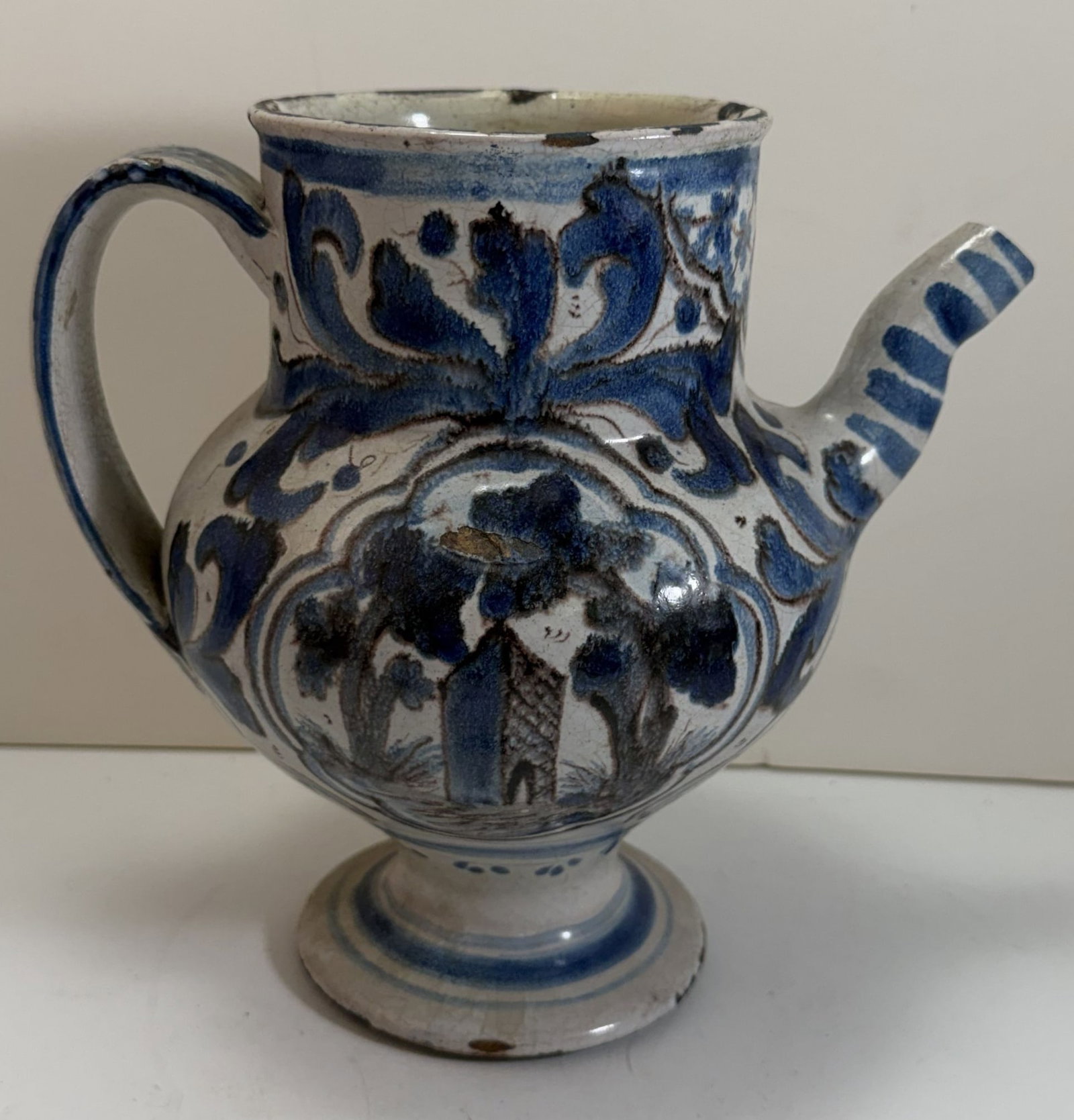 Dutch or Italian Majolica Tin Glazed Spouted Albarello, 17th Century: with blue, white and brown glaze, and decorated on each side with an image of a building and a tree, with some minor scattered chips, some filled. Height: 8 1/4 inches, Width: 6 1/2 inches. Weight: 3