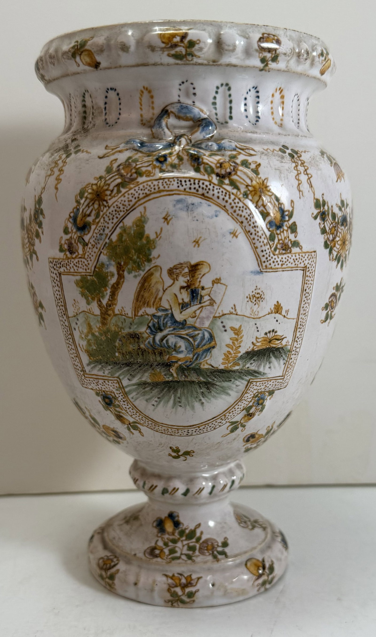 Italian Majolica Albarello, 19th Century: Decorated with nymphs and flowers, one playing a flute, the other writing. With wear as expected from age and use. Height: 7 1/8 inches, Diameter: 4 1/2 inches at the widest. Weight: 13 oz. This item