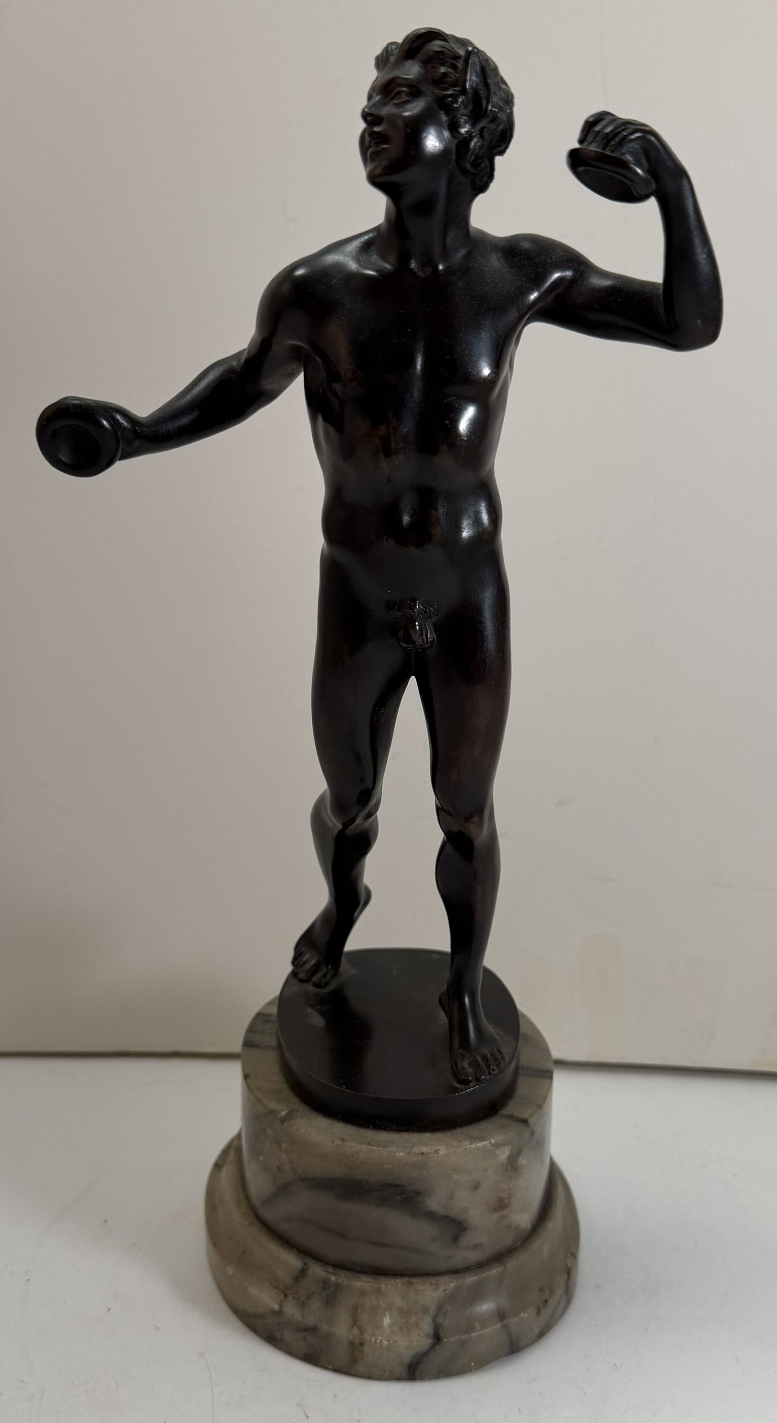 Bronze Sculpture of a Faun Playing Cymbals, After the Antique: On a marble base. Height: the bronze 9 inches, overall 11 3/4 inches with the base, Width: 5 1/2 inches, Depth: 5 inches. Weight: 4 lbs. 6 oz.