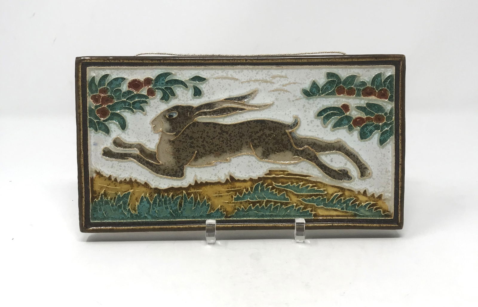 Royal Delft Decorated Pottery Tile, c. 1915.: An Arts and Crafts, Royal Delft Pottery tile/plaque decorated in "Squeeze Bag" technique of a running rabbitt, circa 1915. Size: 9 in. length x 4 7/8 in. width x 1/2 in. thickness, incised "de Porcele