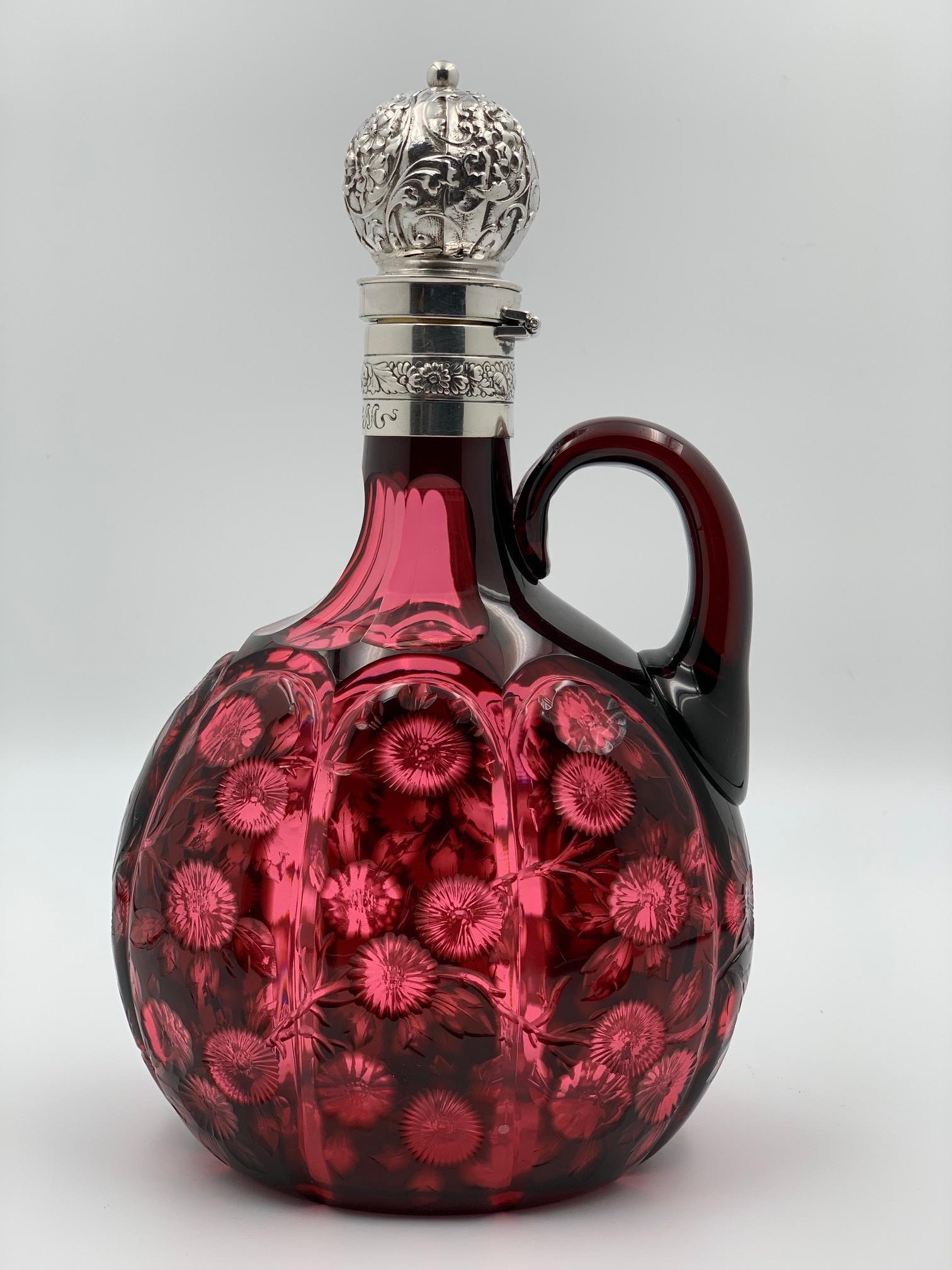 Stevens & Williams Gorham Sterling Cran Cut Glass Jug: Fantastic color on this cut glass decanter by Stevens & Williams. Has deep cranberry color cut to a lighter shade cranberry. Floral design. Hinged sterling repousse top by Gorham Mfg. The hallmark has