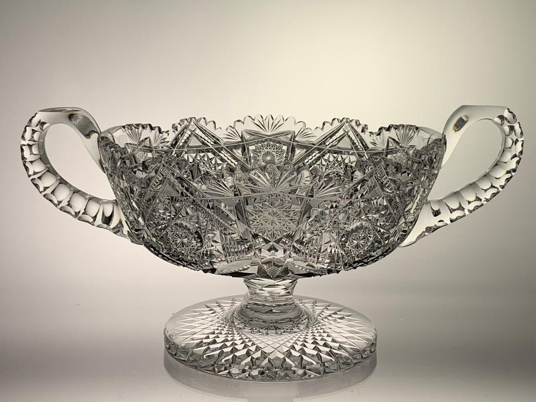 Pairpoint Wamsutta Cut Glass Two Handled Comport: A two handled cut glass comport with a large foot. Cut in the Wamsutta pattern by the Pairpoint Glass Company. American Brilliant Circa 1900. Dimensions: 5 3/4" tall, bowl 9" dia, and 13" wide at the 