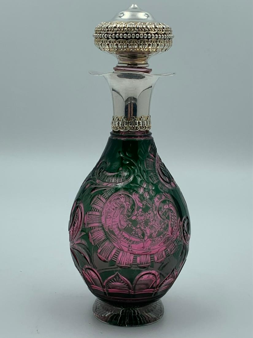 Stevens & Williams Green Cut To Cranberry Glass Perfume: Footed English cut glass perfume bottle by Stevens & Williams. It has beautiful color and is green over cranberry. Silver top has a ruffled edge and is not marked but tested sterling. Stopper is also 