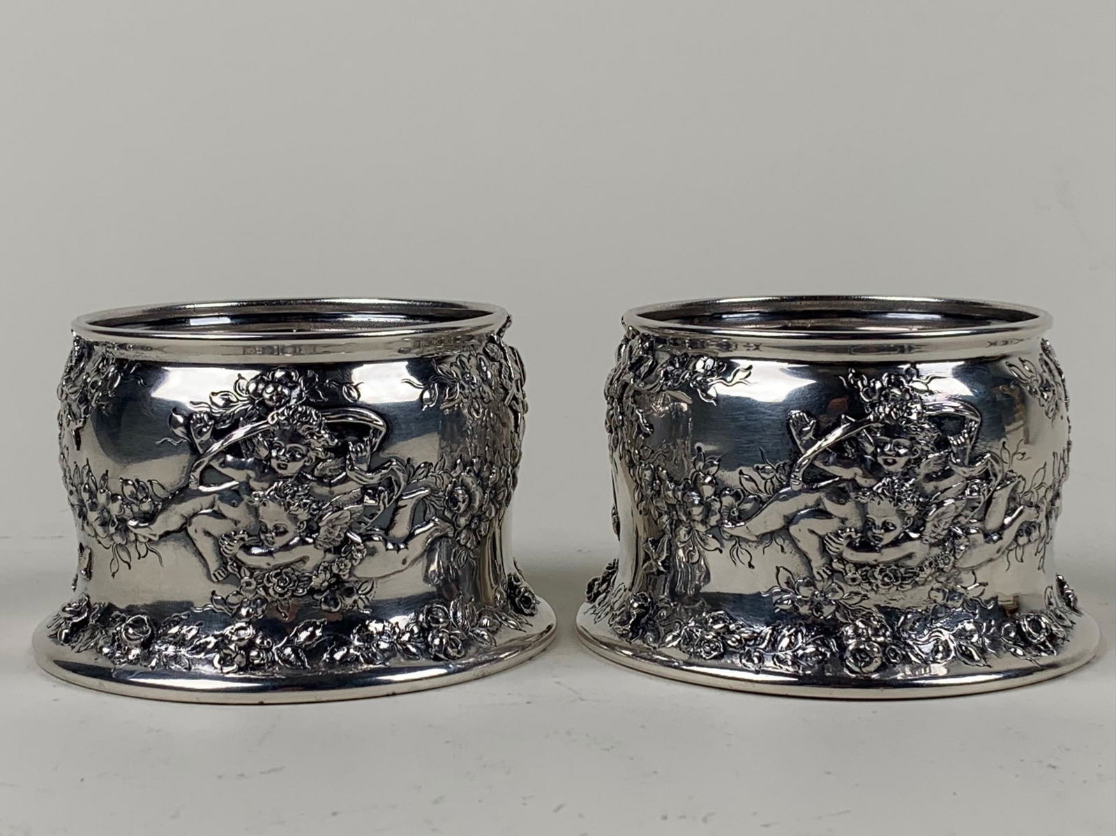 Matched Pair Of Sterling Wine Coasters Tiffany & Co.: A matched pair of sterling wine coasters signed TIFFANY & CO. Decorated with cherubs and floral swags. Circa early 1900's. Dimensions: 2 1/2" h. x 4" dia. Approx. tot. wt. 425 gms. (13.6 tr. Oz.)