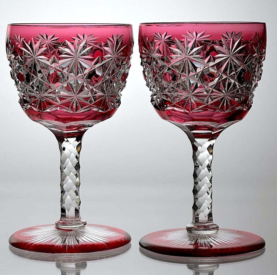 Two Cut Glass Wine Stems Russian Red To Clear: This is a set of two American Brilliant cut glass wine stems. They are red cut to clear and cut in the Russian pattern. They have a red foot with a cut rayed star on the base. The stem is cut with St.