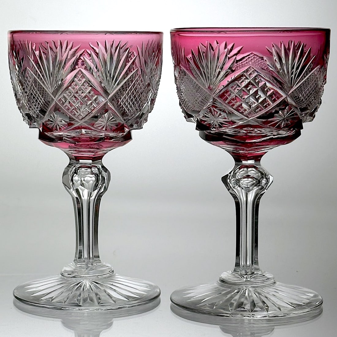 Two Cut Glass Wine Stems Libbey Harvard Red To Clear: A set of two American Brilliant cut glass wine stems. These are cut by Libbey in their Harvard pattern. They are in a pretty ruby color cut to clear. The stems are fluted and have a faceted knob. The 