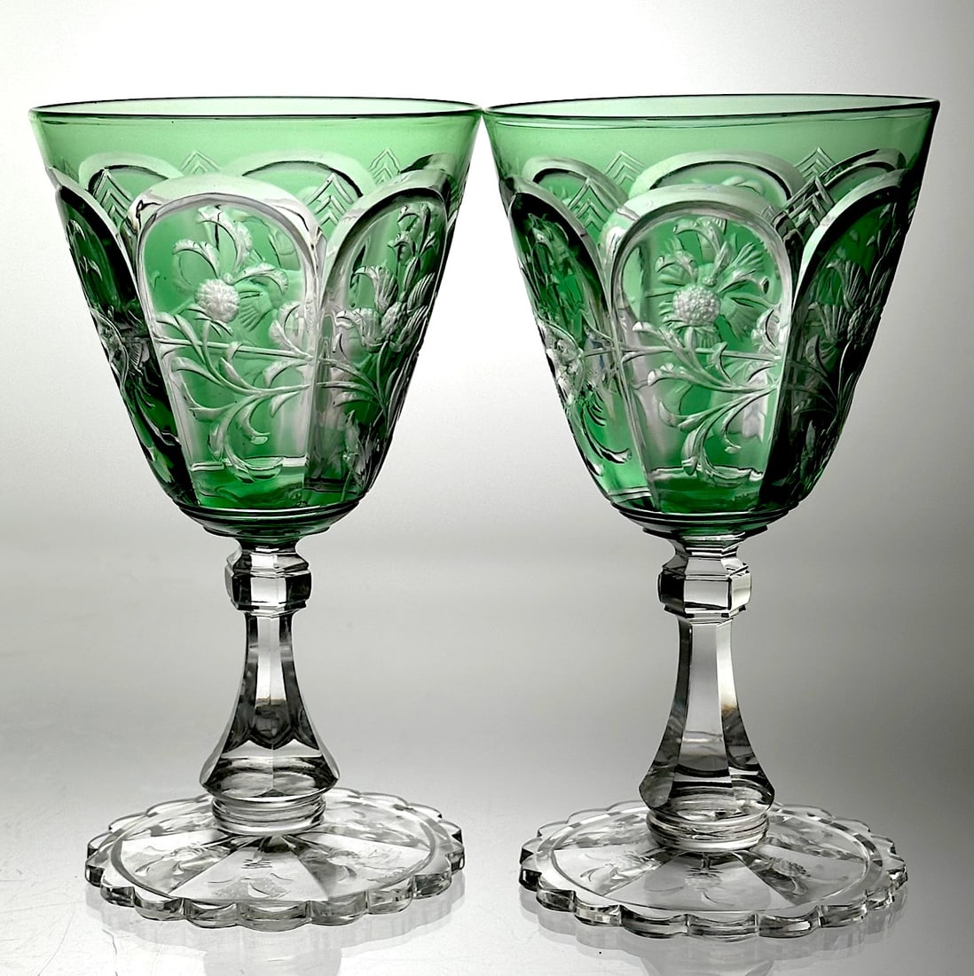 Pair Thos. Webb Cut Glass Wine Stems Green To Clear: This is a pair of wine stems cut by the Thos. Webb company. This have a lovely green color cut to clear. The six panels around the bowl have a floral motif. They have a pyramid fluted stem and a scall