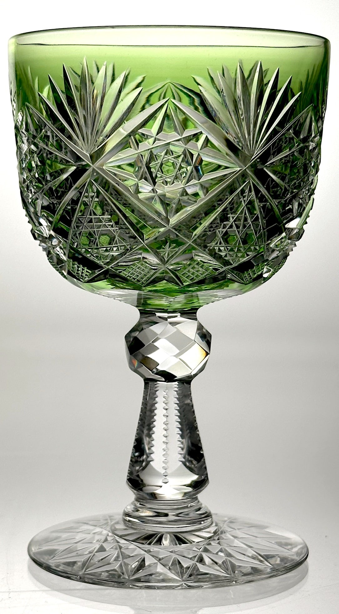 American Brilliant Cut Glass Wine Stem: This is a lovely cut glass wine stem from the American Brilliant period. It is cut with hobstars, fans and cane. The pyramid stem is notched and has a faceted knob. The base is cut with a 16pt. Hobsta