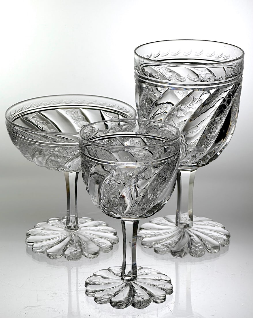 Set of 3 Cut Glass Stems Rock Crystal Pillars & Floral: These are three cut glass and engraved stems. Set has a water goblet, a champagne and a wine stem. They have a floral motif cut over a spiral tusk design. The stems are fluted. The foot is also cut wi