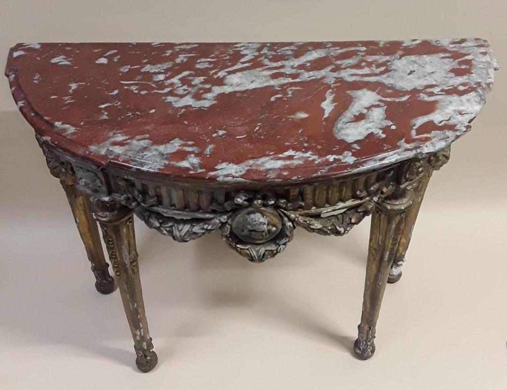 LATE 18TH CENTURY NEO-CLASSICAL CONSOLE TABLE: Italian, possibly, circa 1775 - 1790 Demi-lune carved giltwood table with a marble top (a chip to edge), garlands and a central bow above a wreath enciircling a head in profile. Wonderfully shabby chi