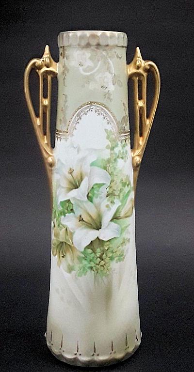 ART NOUVEAU PRUSSIAN VASE: Germany, late 19th early 20th century Maker: Reinhold Schlegelmilch factory Cylindrical double handled porcelain vase with hand painted white lilies and gilding to rim and handles. 9.5" h x 3" diamete