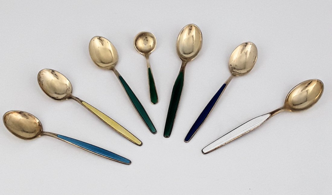 MID-CENTURY NORWEGIAN SILVER AND ENAMEL SPOONS: Norwegian, circa 1950/1960s Maker: two by Theodor Olsen Company and others Nice set of six harlequin enamelled silver-gilt coffee spoons and one demi-tasse spoon. 58 grams