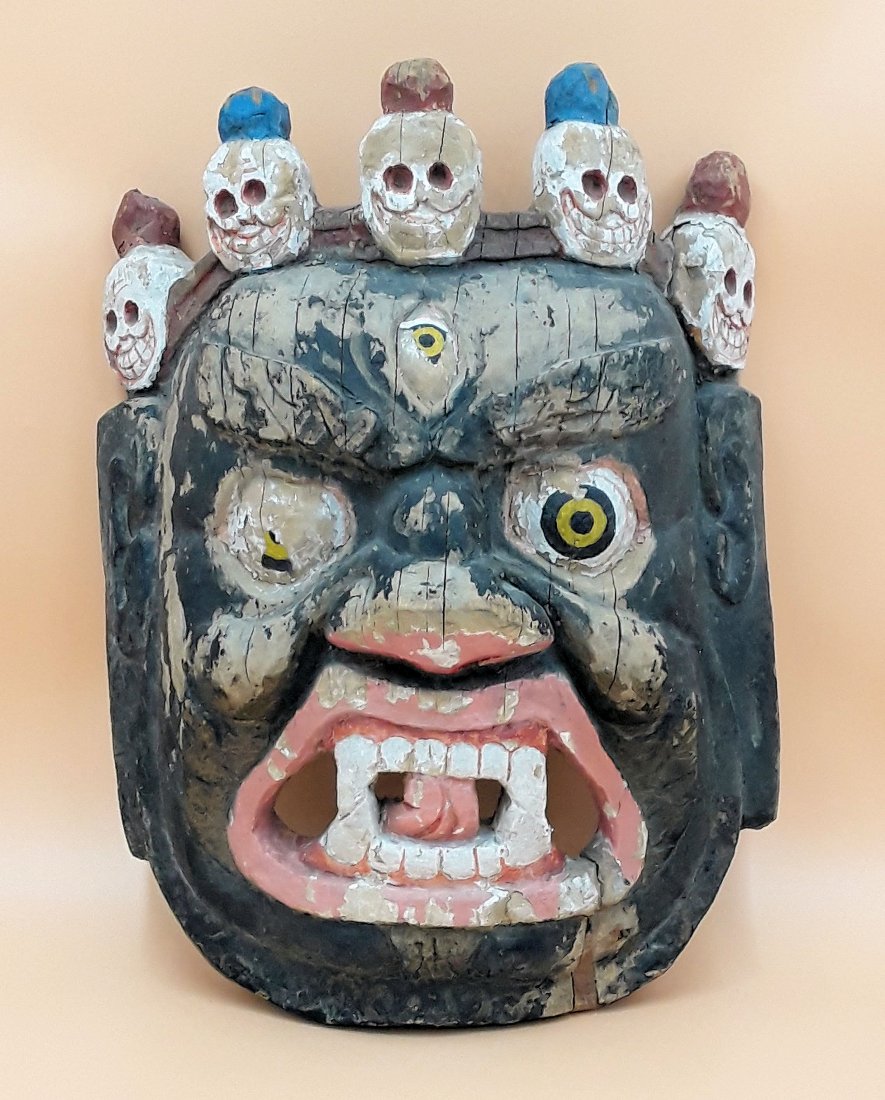 ANTIQUE TIBETAN WOOD DEITY MASK: Old Tibetan Citipati wooden mask, depicting a fearsome wrathful deity adorned with five small skulls, used in Buddhist Cham dances. 17"x12"x7.5". Some paint loss and wood chipped at the bottom.