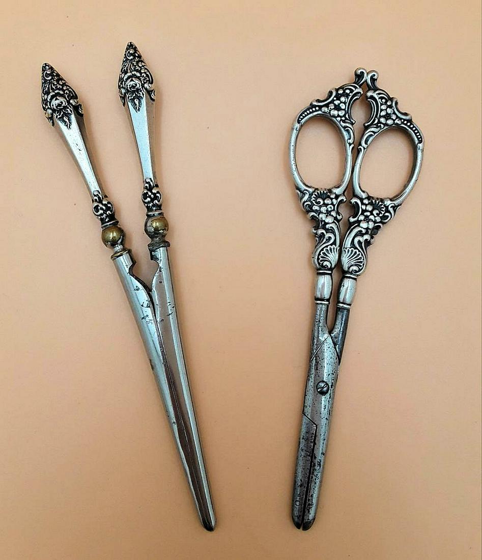 ANTIQUE STERLING HANDLED WARES: Late 19th early 20th century A pair of grape scissors with a floral, scroll and shell design and a hair curler with a rose design. Wear as noted in photos.