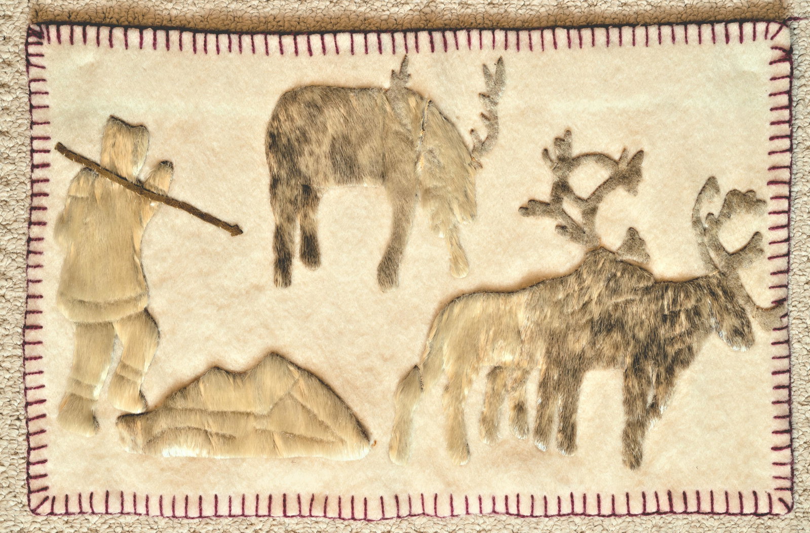 VINTAGE INUIT HANGING: Probably Arviat (Eskimo Point) Nunuvut, late 20th century. "Hunter and Caribou". Applique sealskin on cloth. 14" X 22". Sealskin separation on shoulder of top left caribou