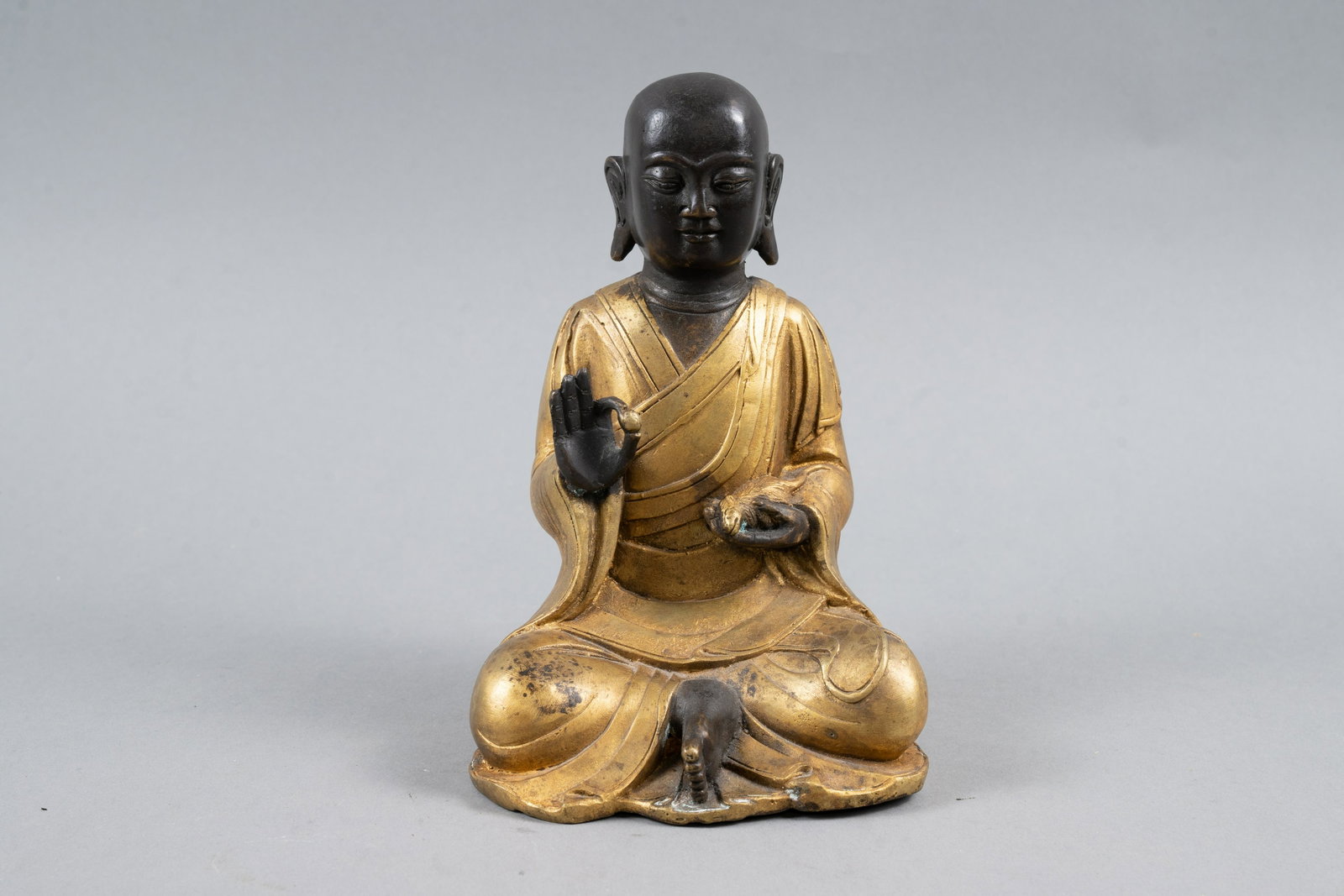 CHINESE BRONZE OF A BUDDHIST MONK: China, second quarter 20th century. A bronze seated figure of a Buddhist monk with gilded robes. 6.75" h x 4.25"w x 3.75"d