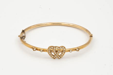 ANTIQUE 14K GOLD BANGLE: Probably first quarter 20th century. This is a fine 14 K yellow gold bangle having intertwined hearts set with seed pearls. 2.75' diameter and 8.5 grams.