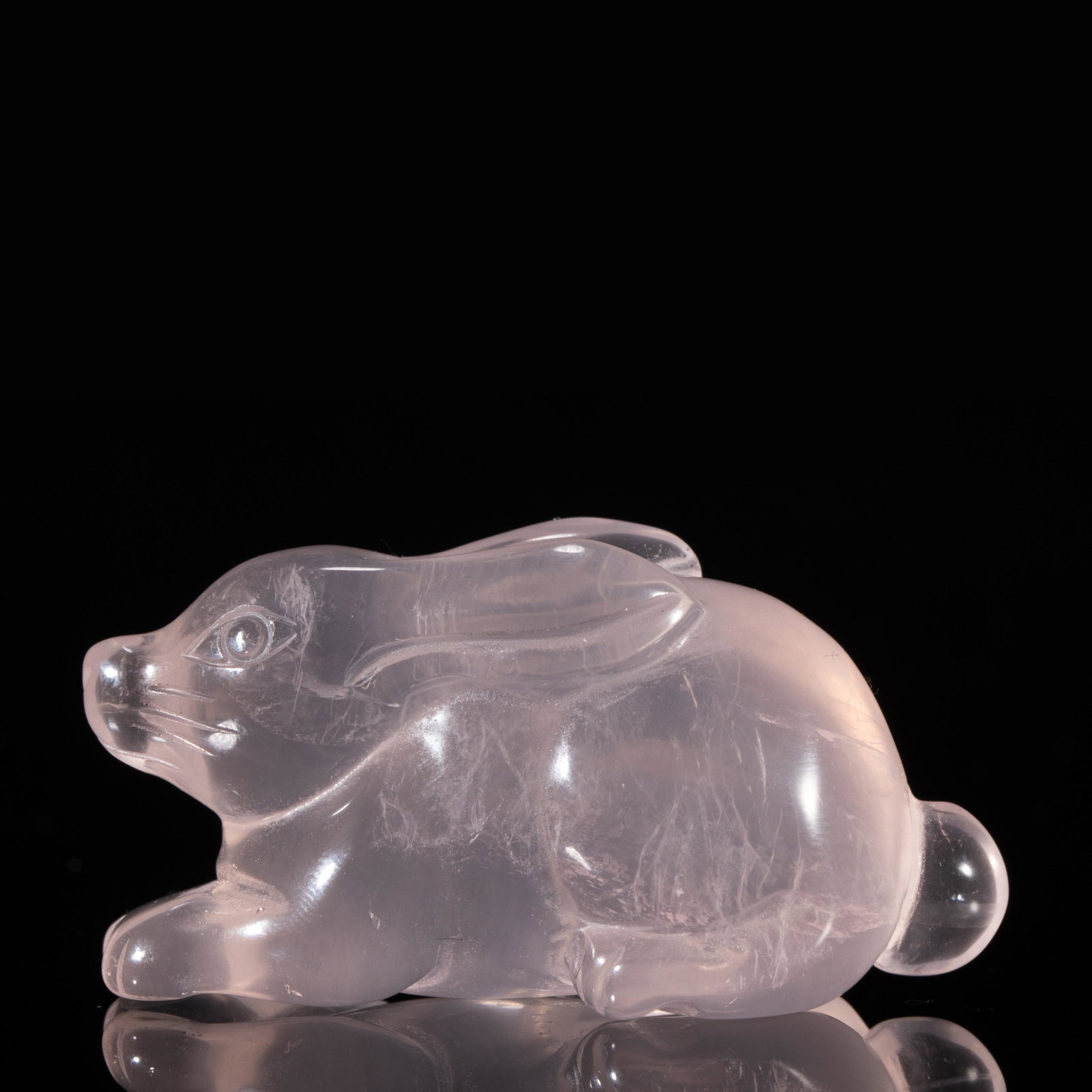A CARVED ROCK CRYSTAL RABBIT: A CARVED ROCK CRYSTAL RABBIT 5.2 cm L x 2.3 cm W x 2.8 cm H x Weight 40 gram. Carved the recumbent animal crouching on four legs, with head raised facing forward, long ears tucked on its back, and wit