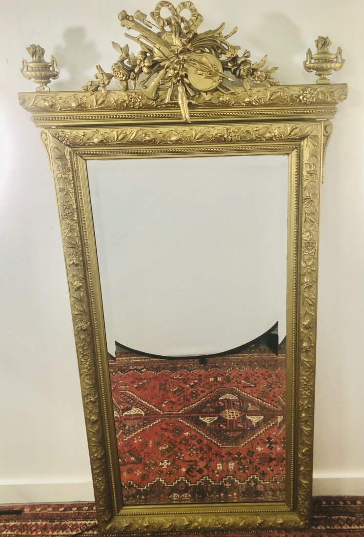 Antique Hand Carved Gilt Wood Trumeau Mirror: Antique hand carved large gilt wood trumeau mirror featuring intricate design. each top side presents a torch design and the middle has an elaborated design of flowers , bow and violin instrument. Mir