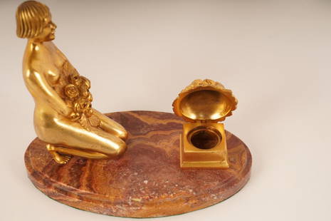 Gilt Bronze Figural Inkwell: Likely Austrian, c1900. Depicting a nude female holding a bouquet of flowers kneeling on a marble base in front of a bouquet of flowers that opens to hold the well.