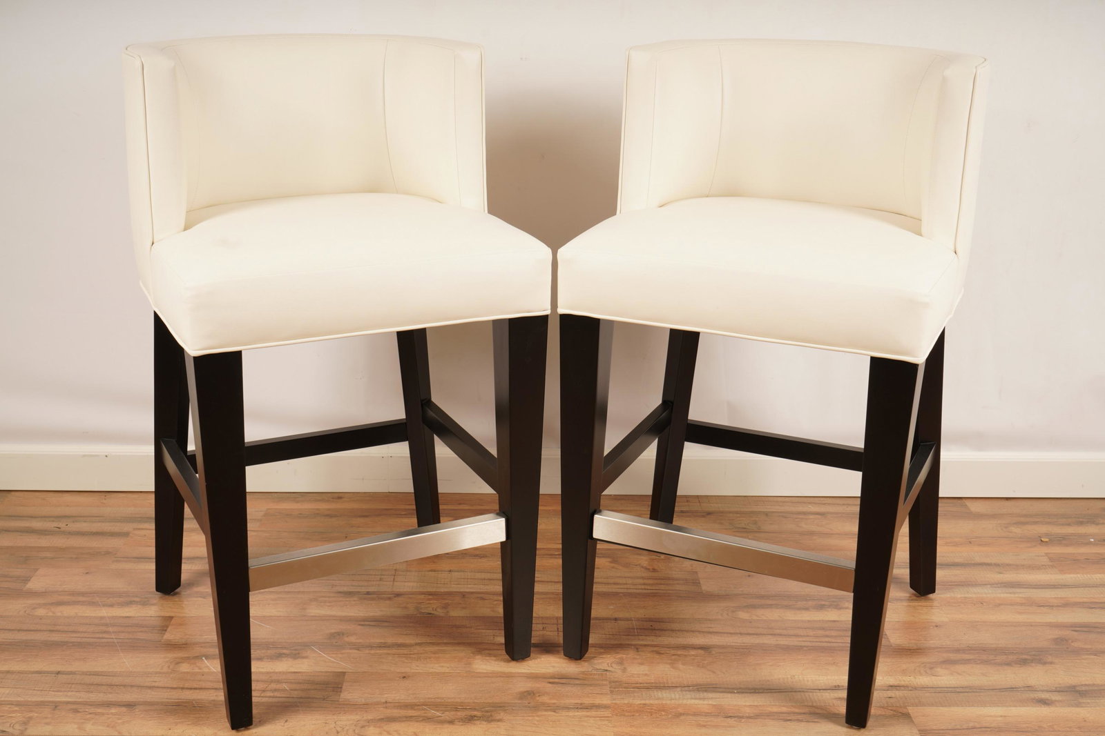 Stewart Furniture Pair Upholstered Barstools: Pair (2) of stools by Stewart Furniture Design with modern design. White top on brown tapered legs and aluminum colored footrest bar. Each stool H 40 1/2" x W 23" x D 23".
