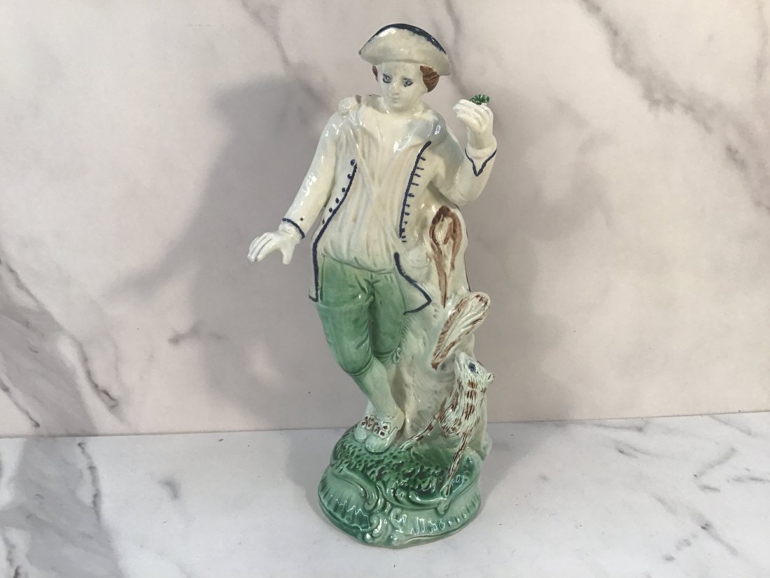 English Staffordshire Creamware 9" Figure Gentleman with Dog: A rare form in creamware showing a gentleman holding a flower, raised on a green base accompanied by a dog. Charming.