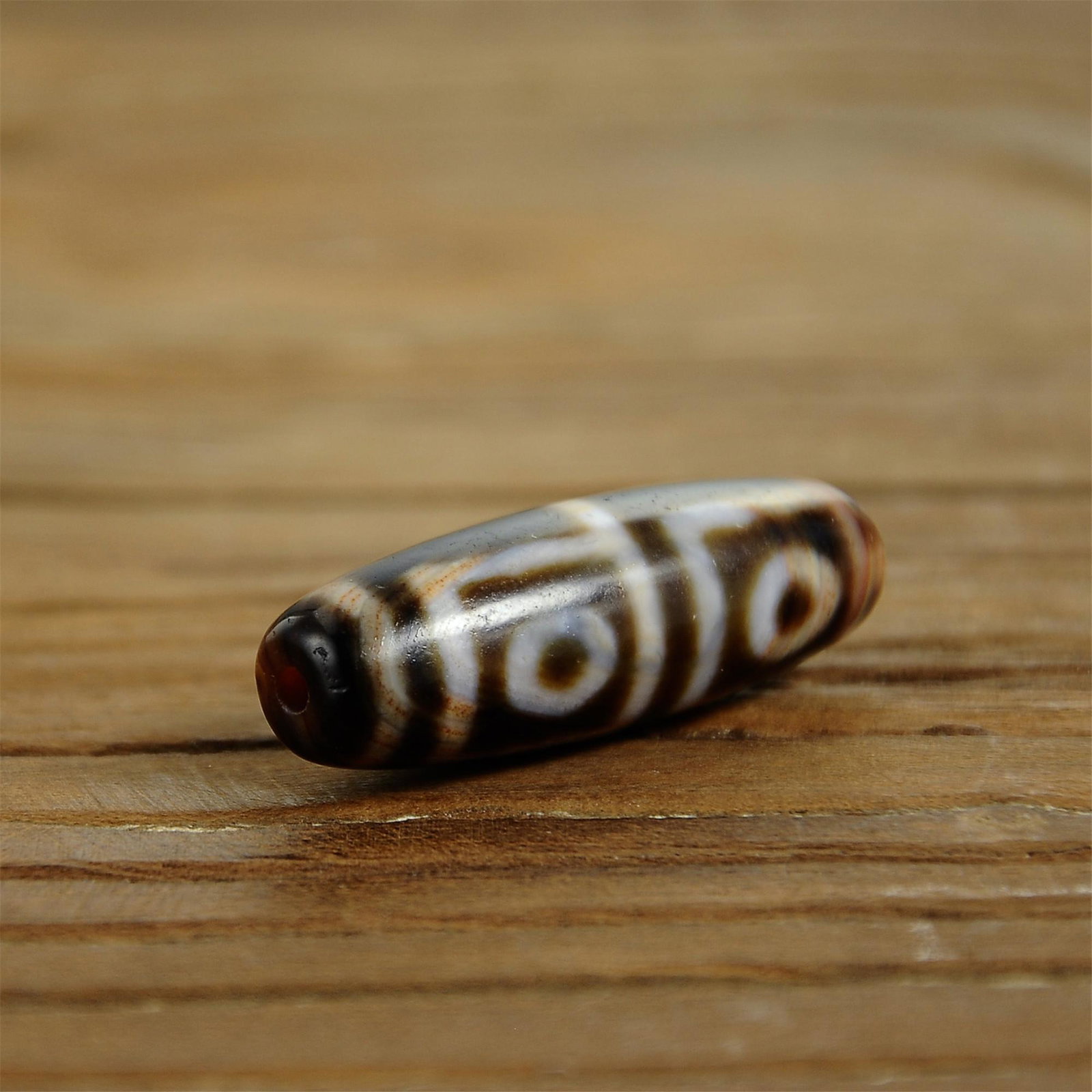 Tibetan 4-eye dzi bead: 20th C / Size: about 36x12x12mm/ Tibetan vintage agate dzi beads. The agate beads have round horseshoe marks and erythema, which are traces of oxidative wear caused by long-term use. An important patr