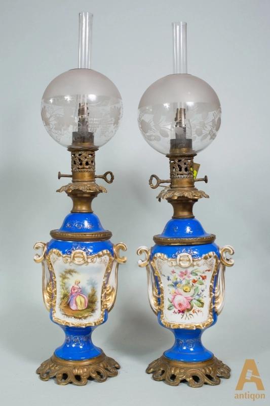 Twin porcelain kerosene lamps.: Pair of porcelain kerosene lamps of rare preservation and quality with original round lampshades and porcelain painting. With scenes of gallant festivities and a flower arrangement on the back. The gl